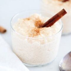 A glass full of Mexican rice pudding garnished with a cinnamon stick.