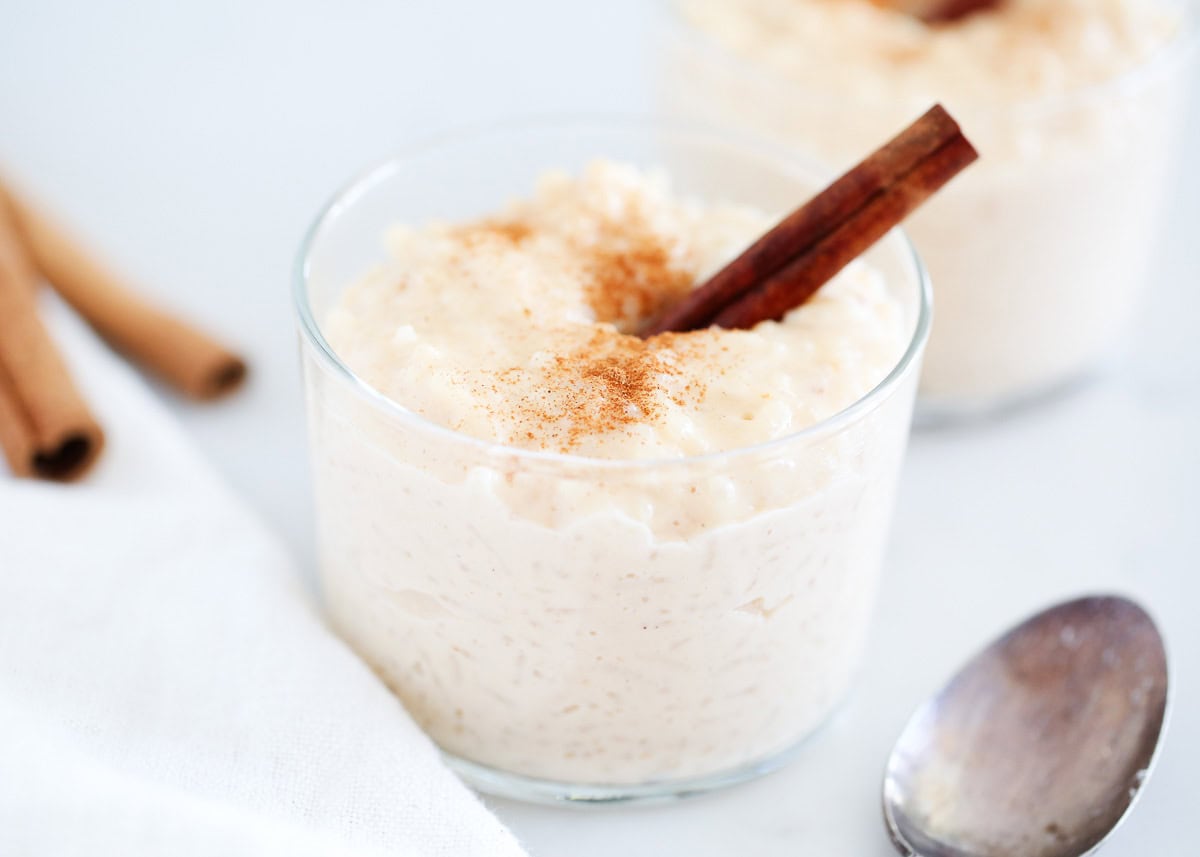 A glass full of Mexican rice pudding garnished with a cinnamon stick.