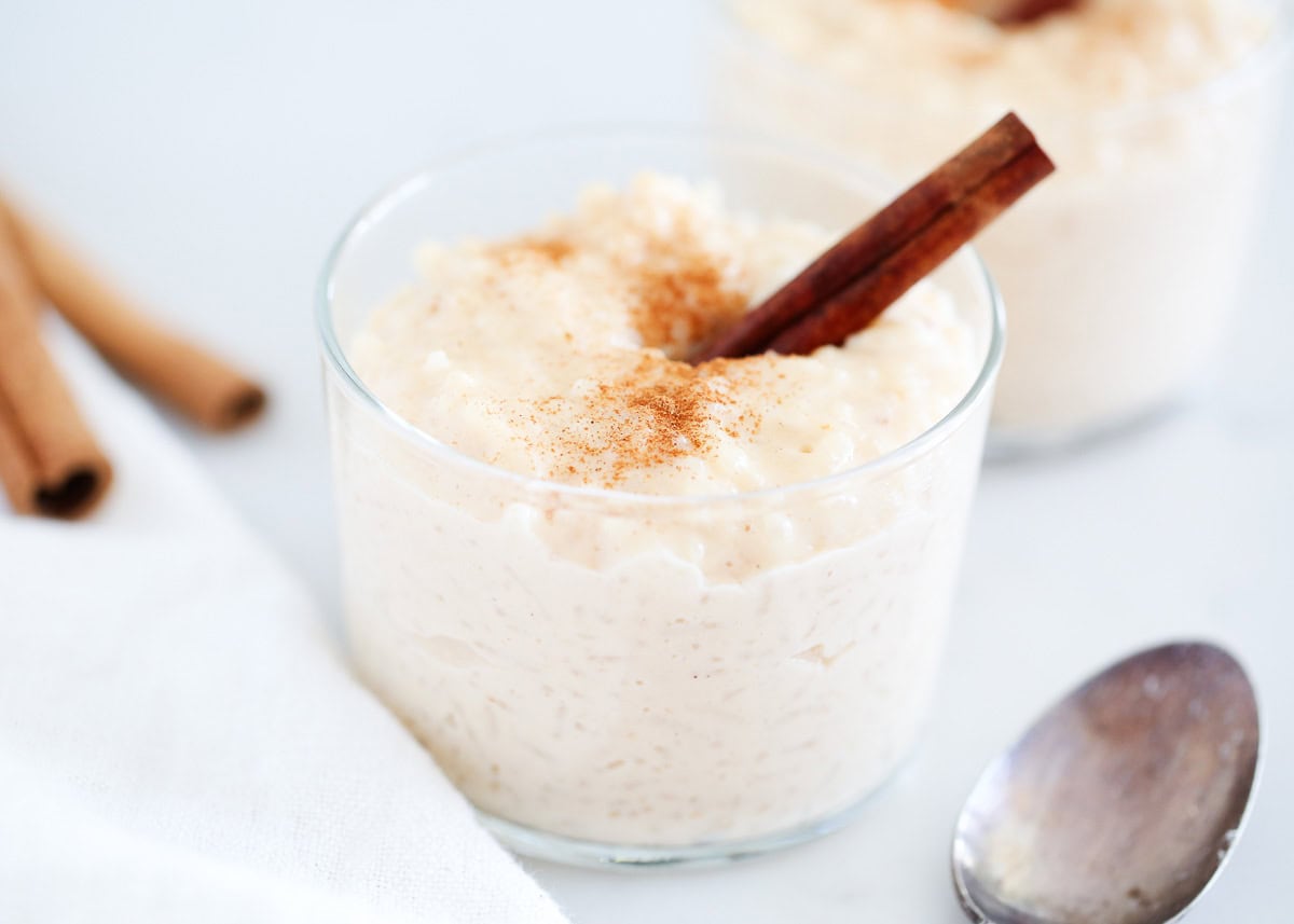This arroz con leche (Mexican rice pudding) is an ultra-creamy rice pudding lightly spiced with cinnamon. Served hot or cold, you will love this Mexican dessert! A glass full of Mexican rice pudding garnished with a cinnamon stick.