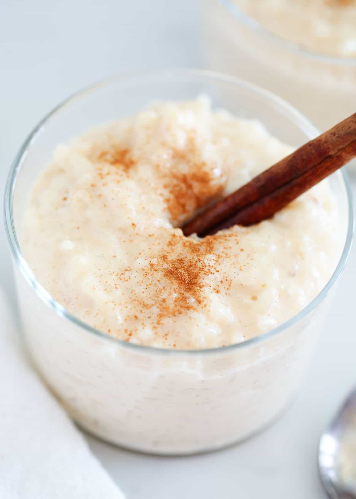 A cup of Mexican rice pudding garnished with a cinnamon stick. 
