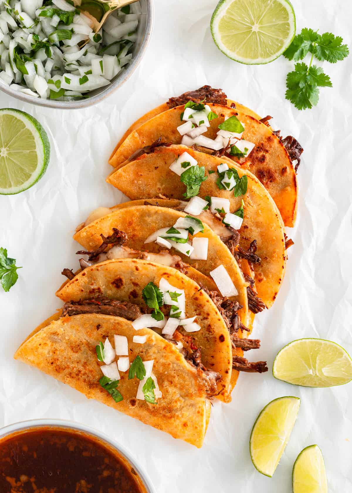 Birria tacos on a piece of parchment paper.