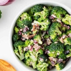 Broccoli bacon salad with cranberries and sunflower kernels in a white bowl.