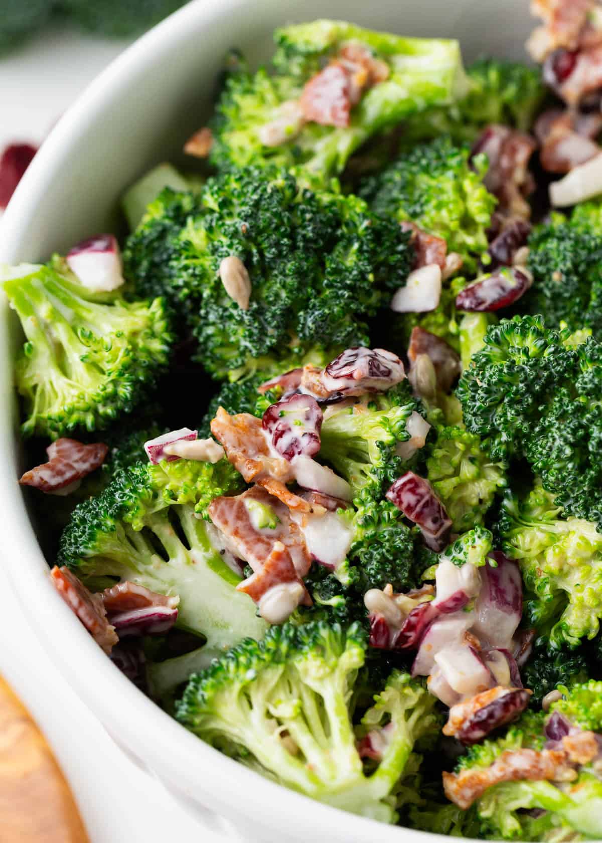 Broccoli salad with bacon in a white bowl.