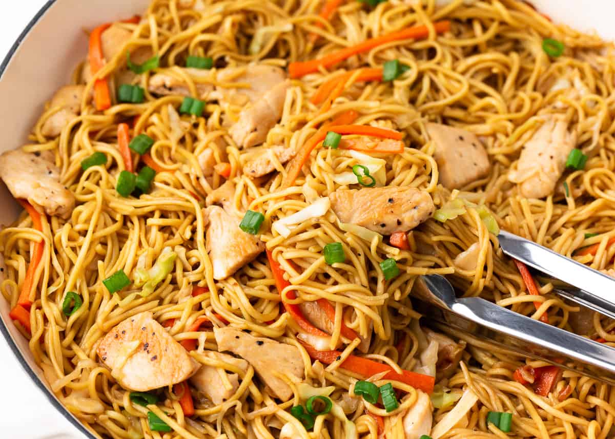 Chicken chow mein cooking in a skillet. 
