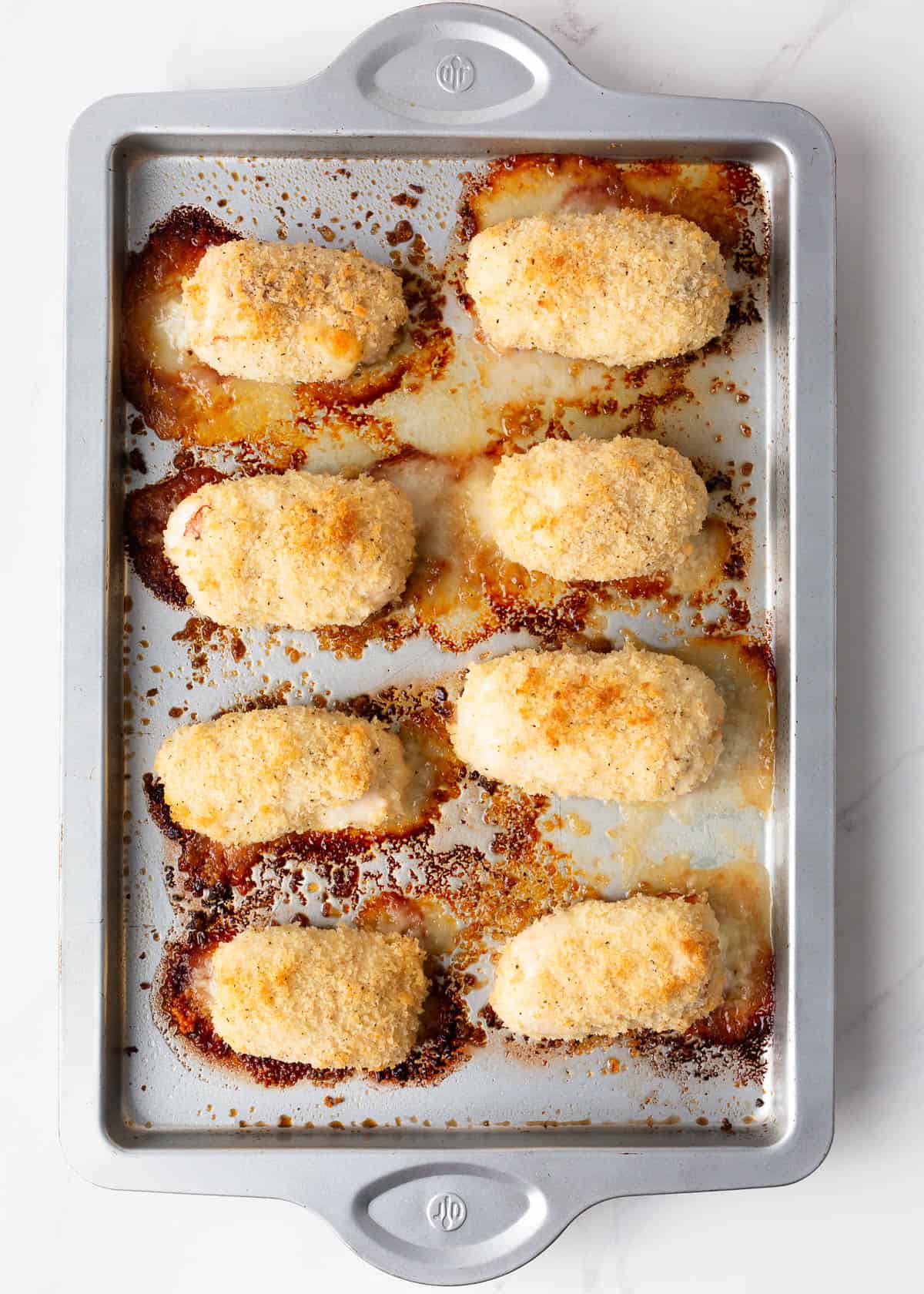 Chicken cordon bleu on metal baking sheet.