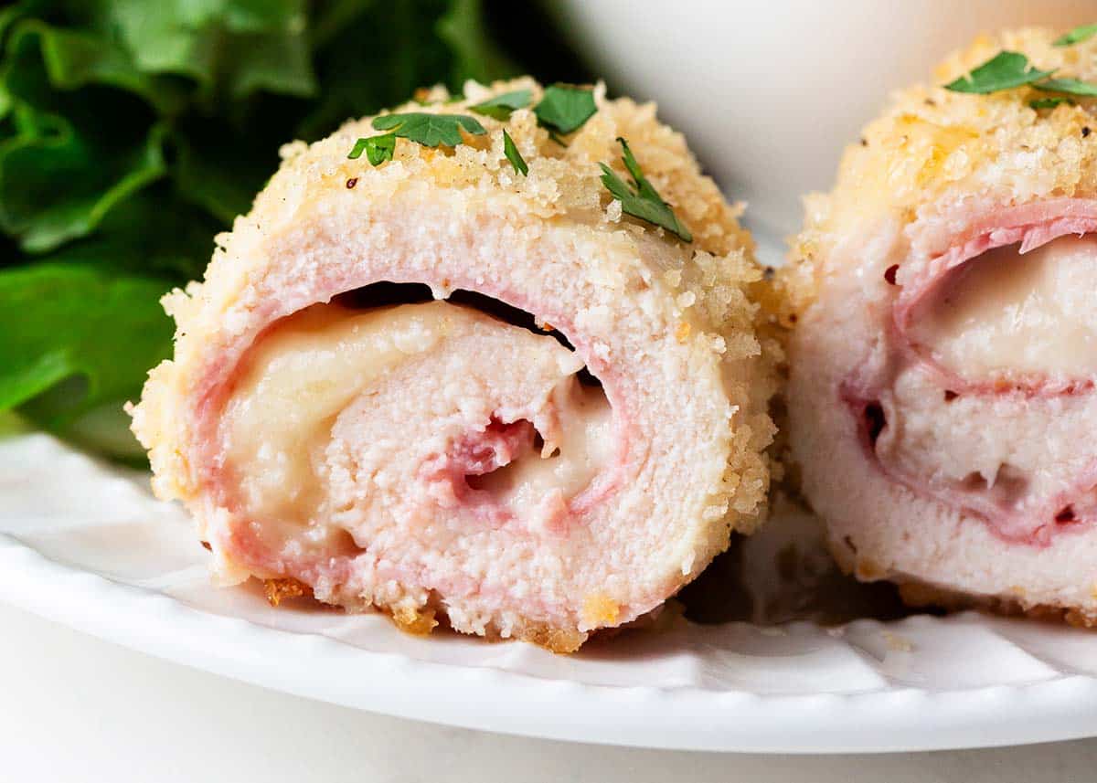 Sliced chicken cordon bleu on white plate.