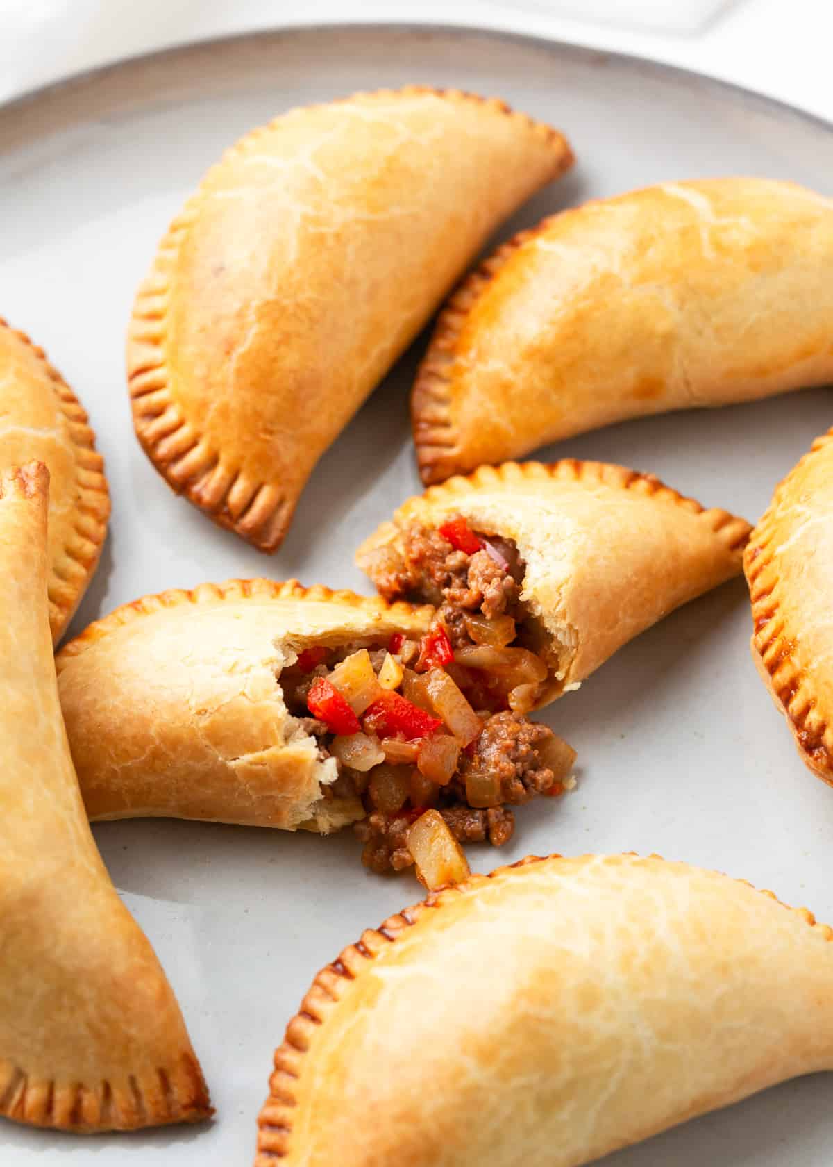 Beef empanadas on a white plate with one split in half.