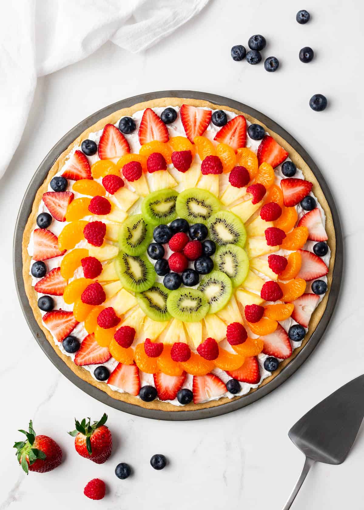 Fruit pizza on marble counter.