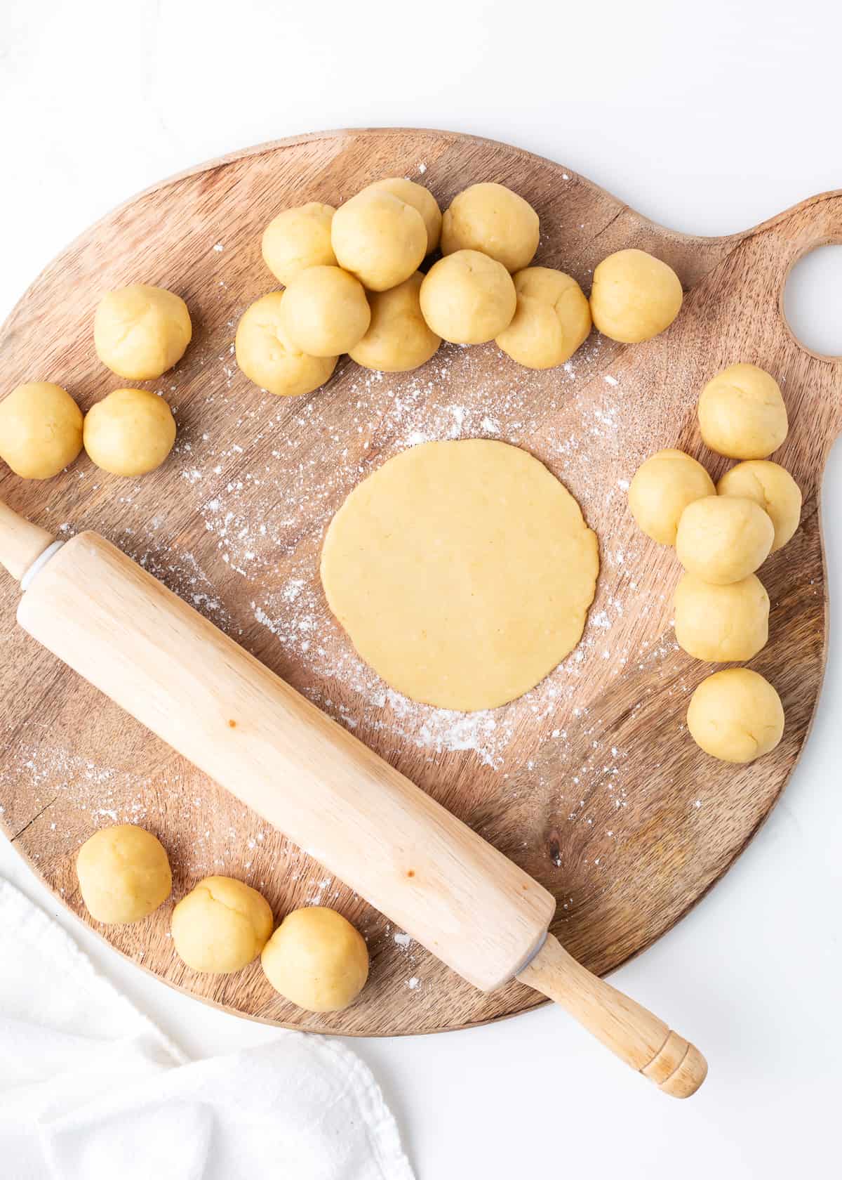 Rolling empanada dough on wooden board.