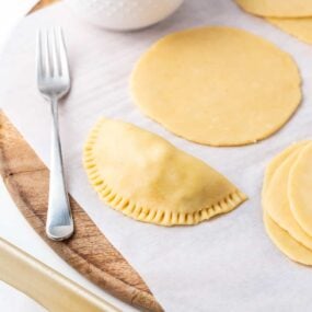 Making empanada dough on wooden board.