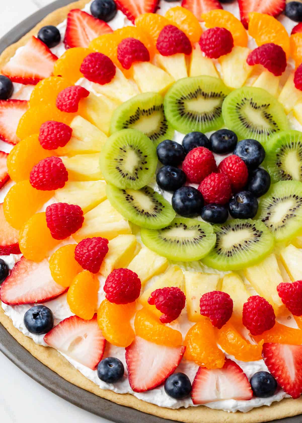 Close up of fruit pizza on a marble counter.