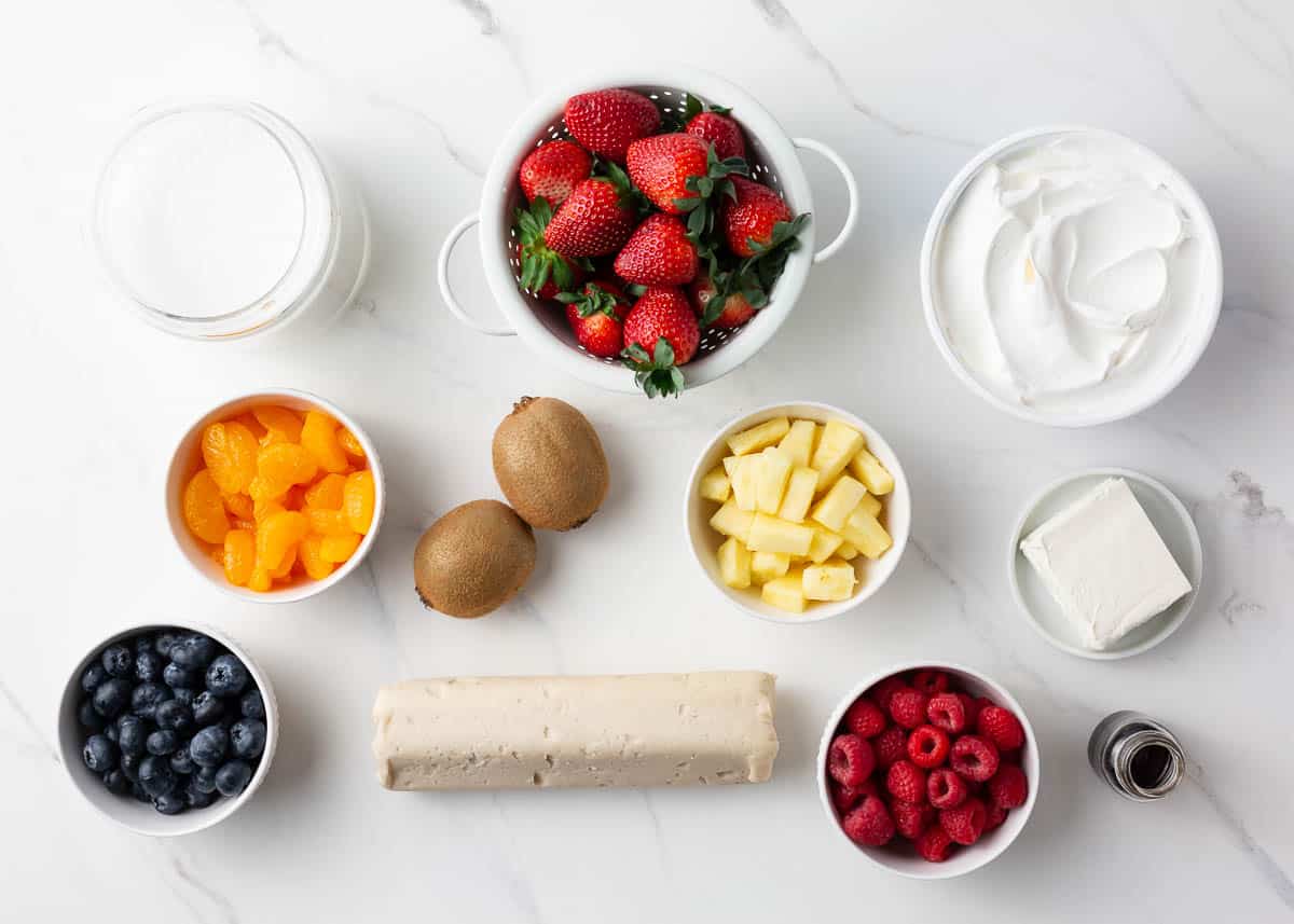 Sugar cookie dough, strawberries, kiwi, pineapple, blueberries, raspberries, mandarin oranges, cream cheese, cool whip and sugar.