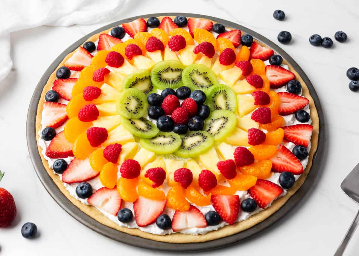 Fruit pizza on a marble counter.