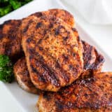 Grilled pork chops on a white plate with parsley.