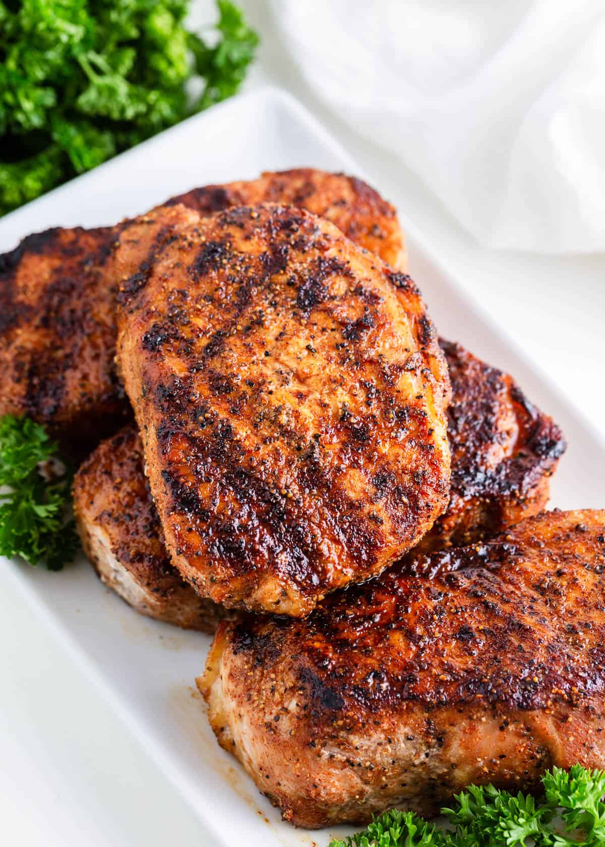 Grilled pork chops on a white plate with parsley.