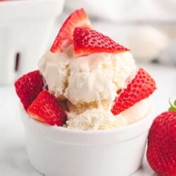 Homemade vanilla ice cream in a bowl with sliced strawberries.