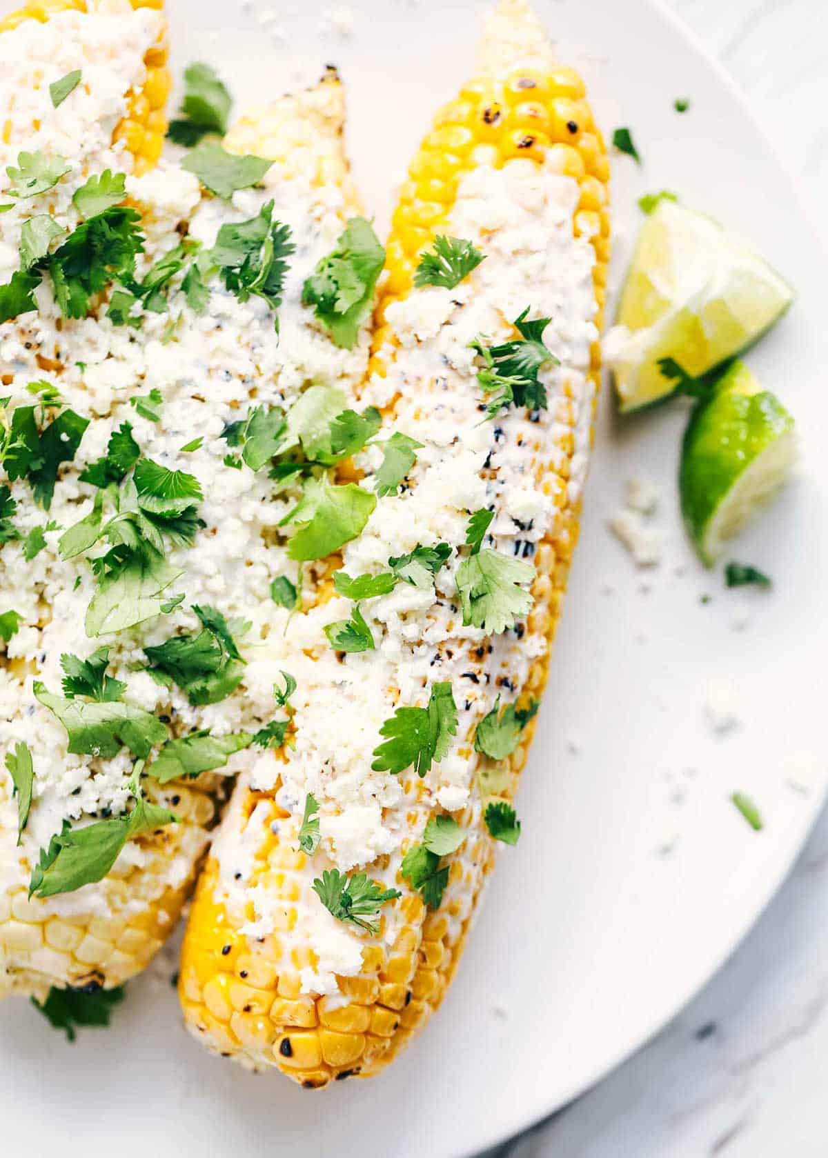 Up close photo of Mexican street corn on a white plate.