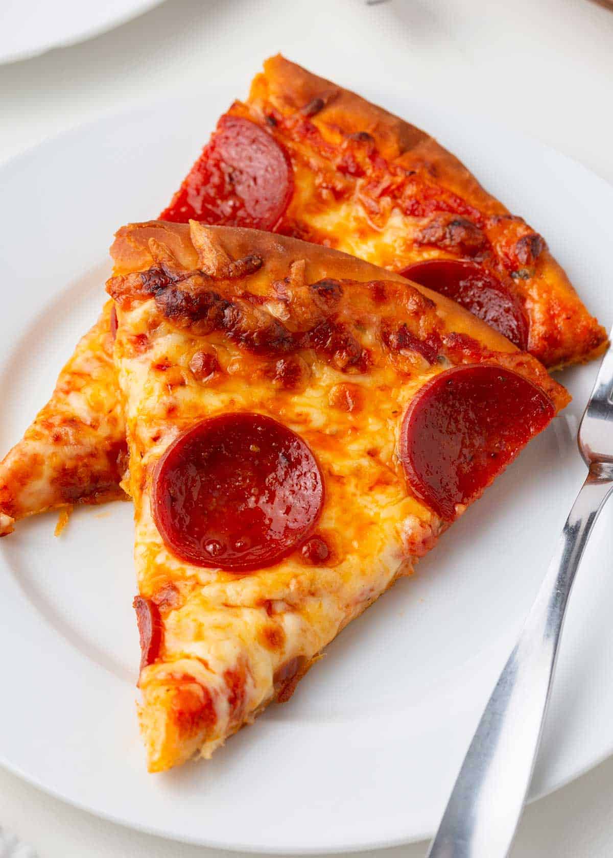 Slice of pepperoni pizza on plate. 
