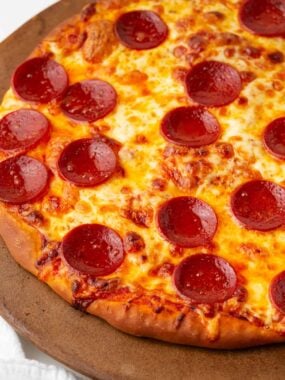 Homemade pepperoni pizza on a pizza stone with crisp pepperoni and gooey melty cheese.