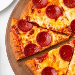 Sliced homemade pepperoni pizza on a baking stone.