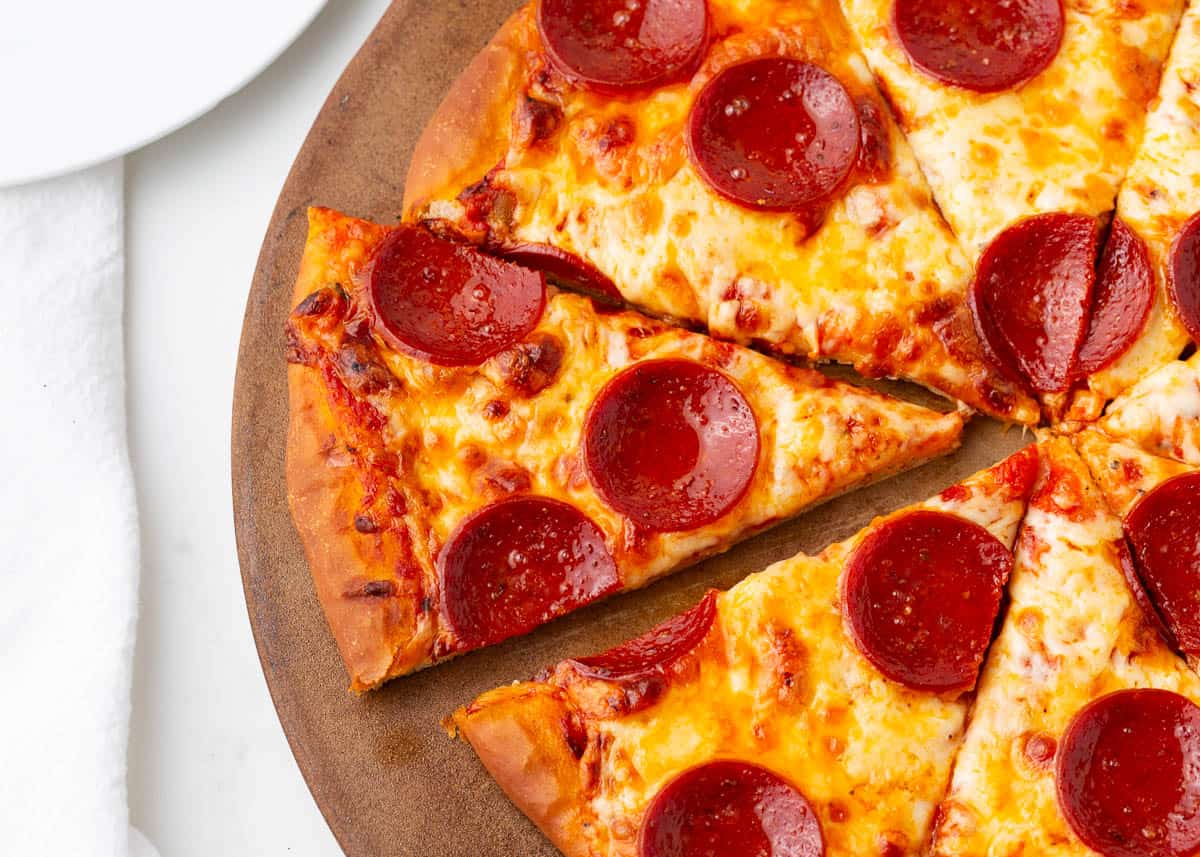 Sliced pepperoni pizza on a baking stone. 