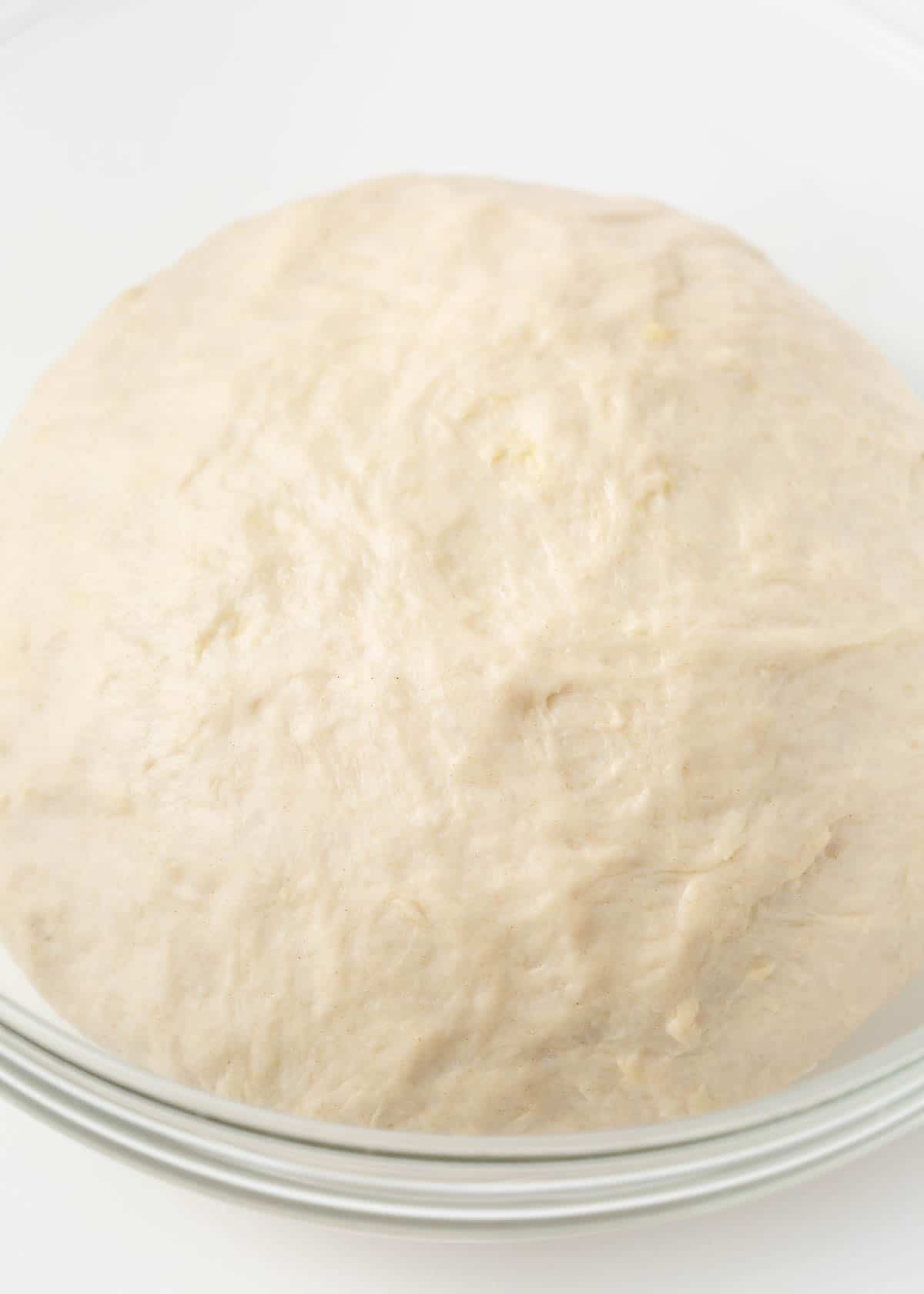 Pizza dough in a clear bowl