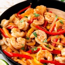Shrimp fajitas cooked in a skillet with cilantro on top.