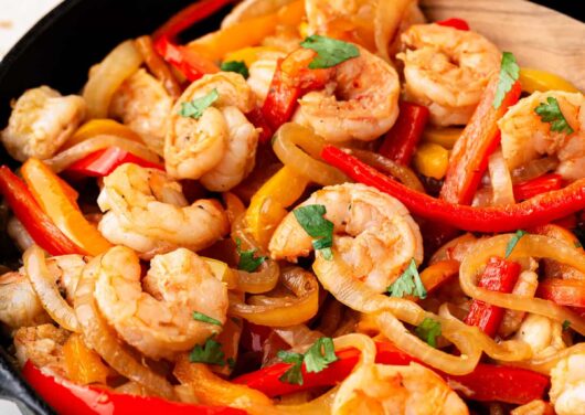 Shrimp fajitas cooked in a skillet with cilantro on top.