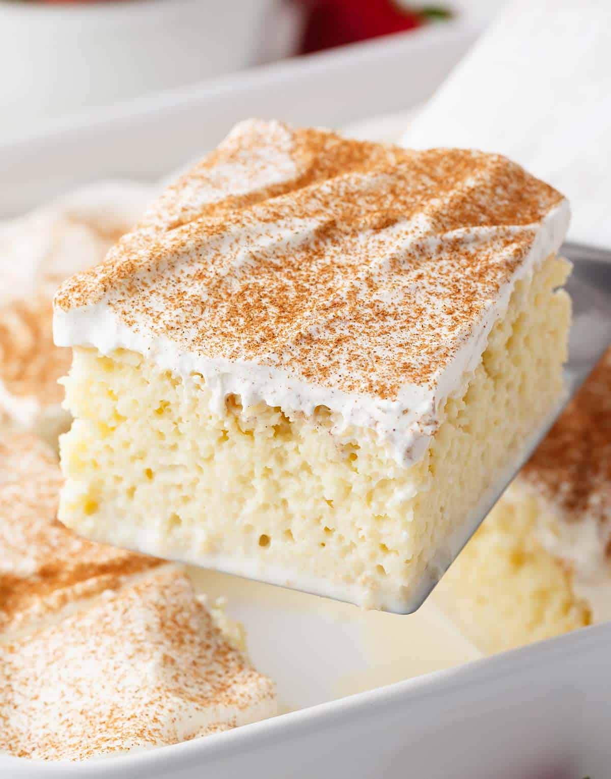 Tres leche cake being served from a pan.