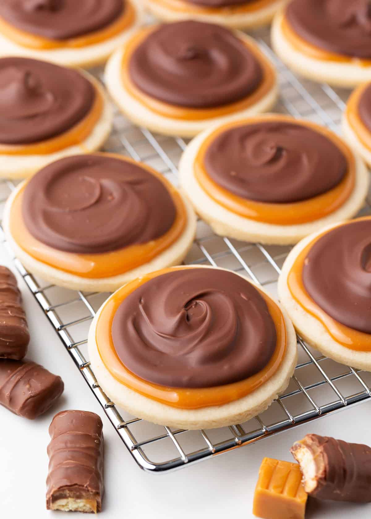 Twix cookies on cooling rack with Twix cookie bar pieces on the counter.