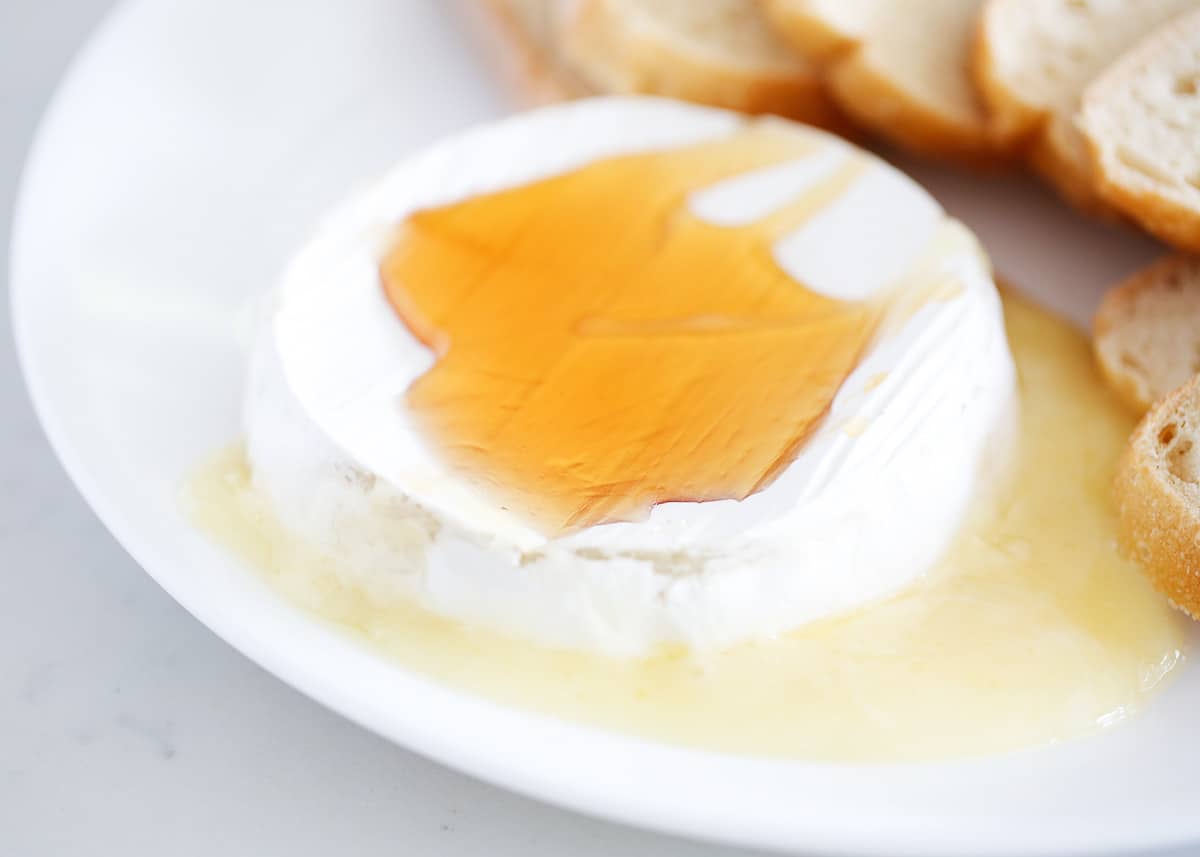 Baked brie with honey is a simple and delicious appetizer recipe that's always a crowd-pleaser! This baked brie is so creamy, and rich and tastes amazing paired with the sweetness of the honey. Baked brie with honey over top.