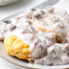 Homemade biscuits and gravy on a plate with a fork.