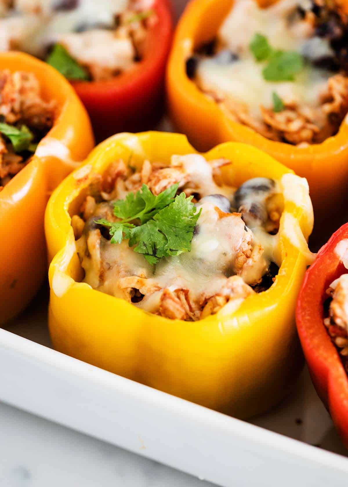 Bell peppers stuffed with chicken in a baking dish. 