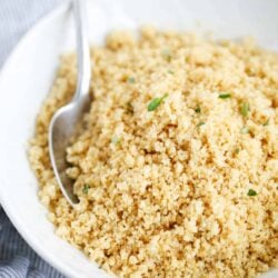 Couscous in a white bowl with a spoon.