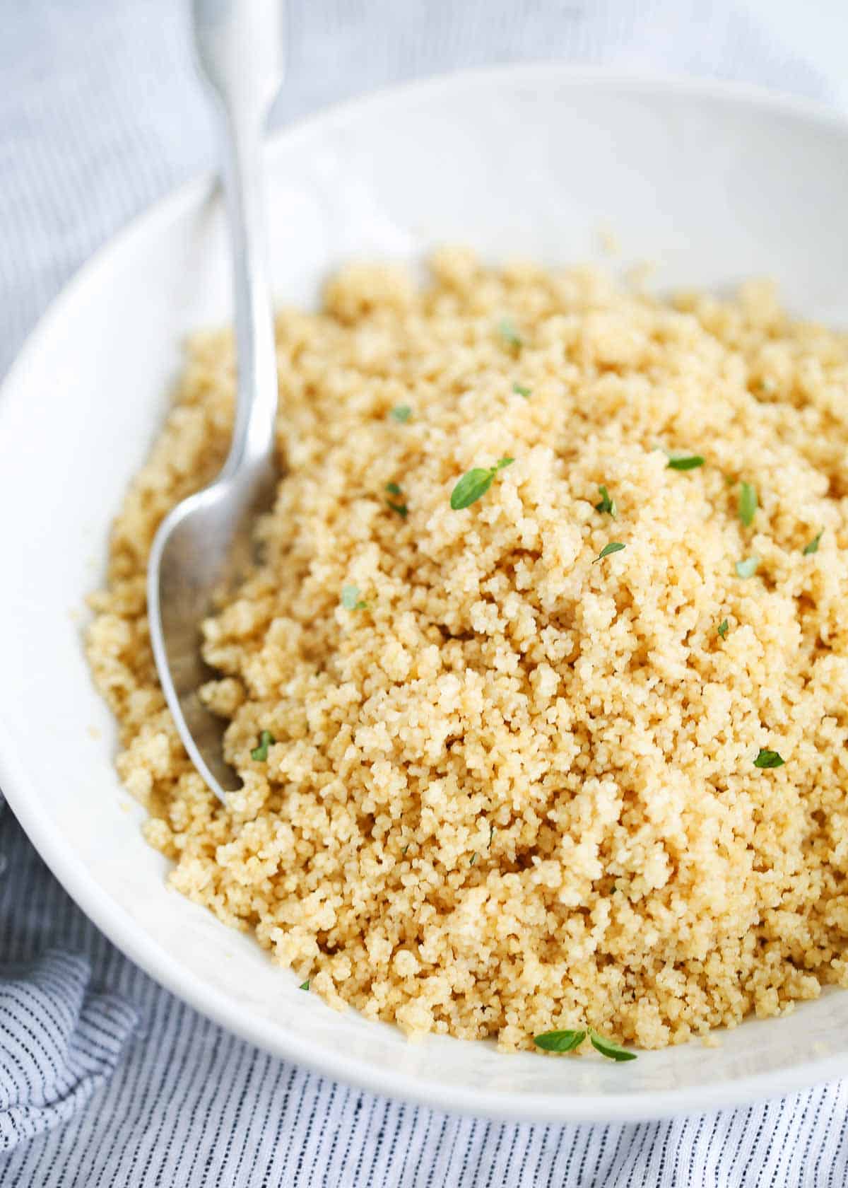 Couscous in a white bowl with a spoon.