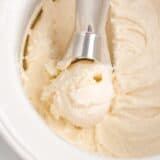 Homemade vanilla ice cream being scooped out of ice cream maker.