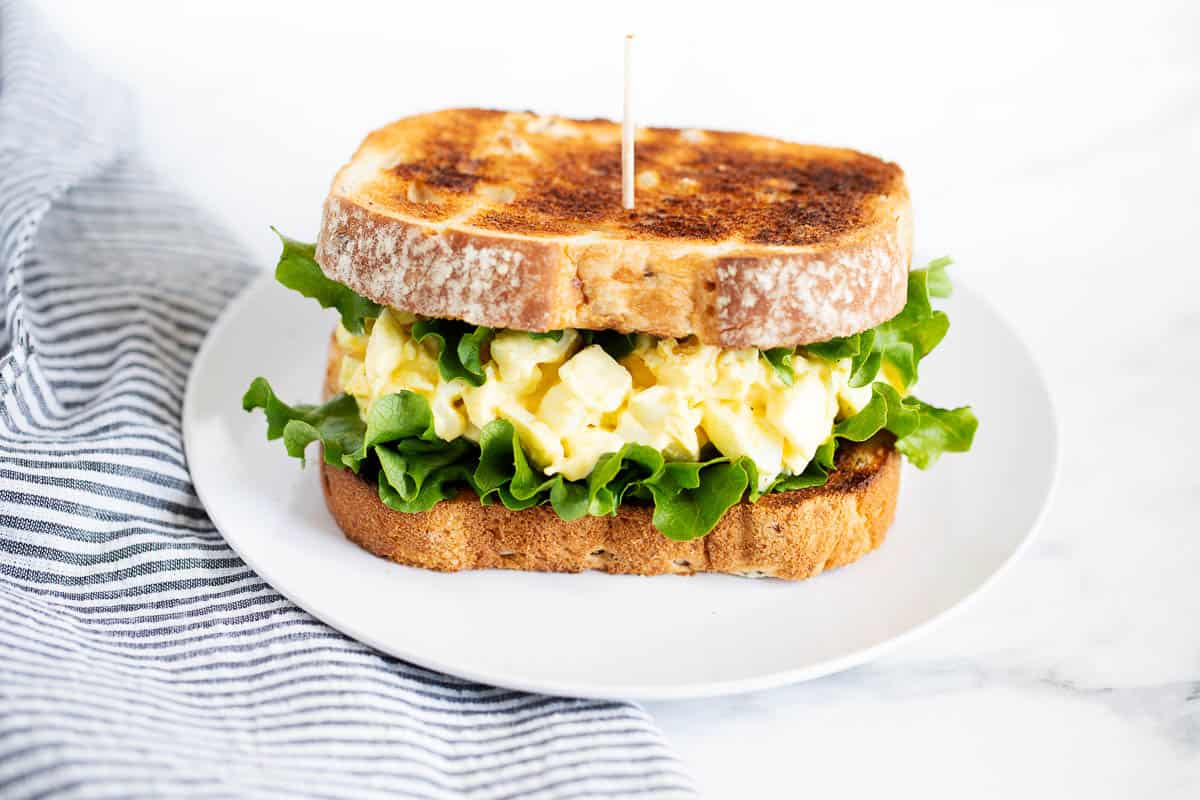 Egg salad sandwich on a white plate. 