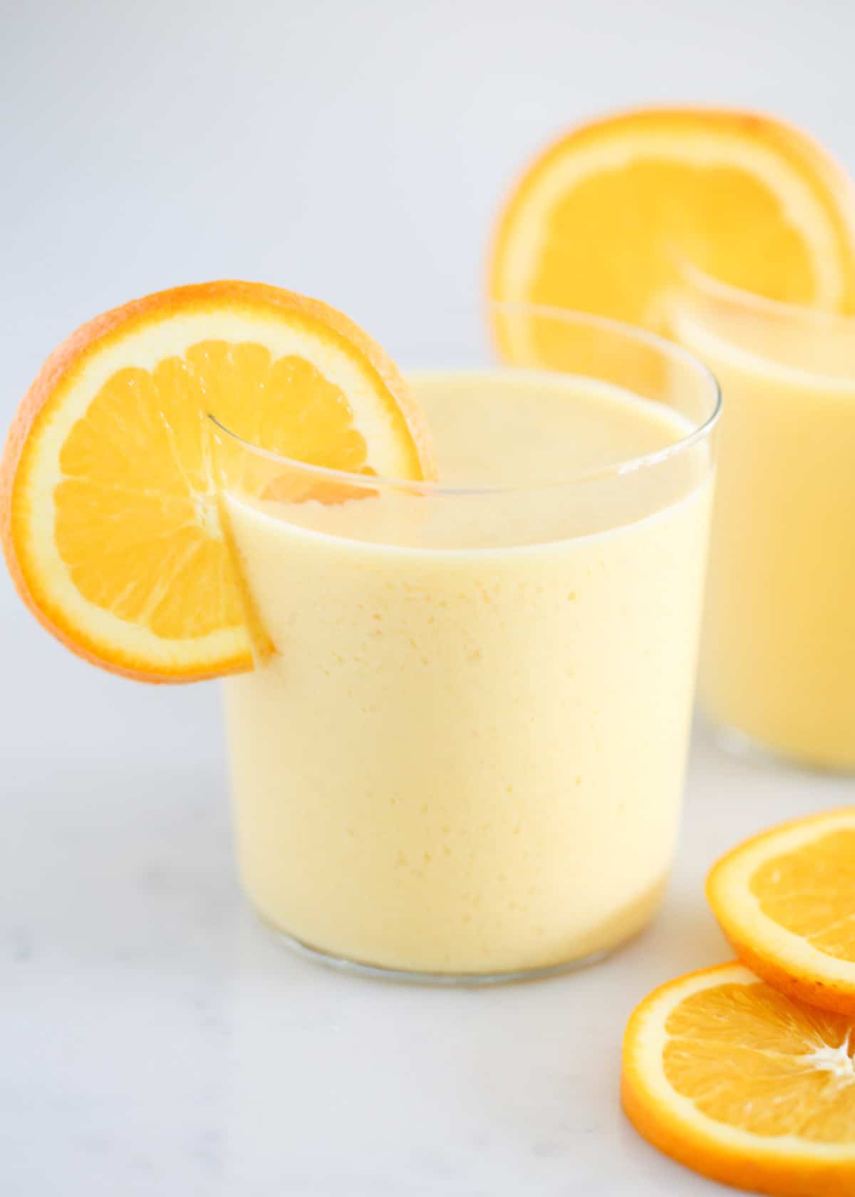 Orange Julius in a glass cup with orange slices.