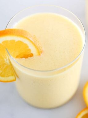 Orange Julius in a cup with orange slices.