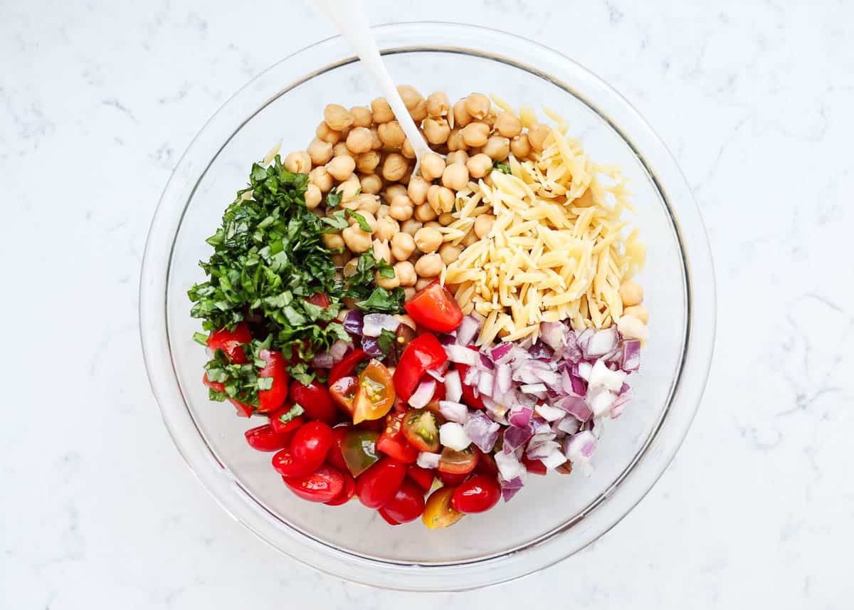 Orzo salad ingredients in a glass bowl.