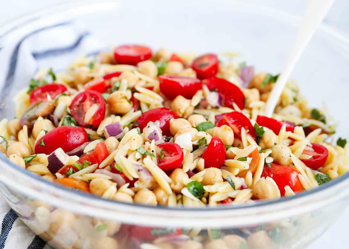 Orzo salad in a bowl with a spoon.