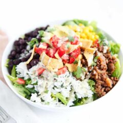 Easy taco salad with rice, taco meat, beans and toppings in a bowl ready to serve.