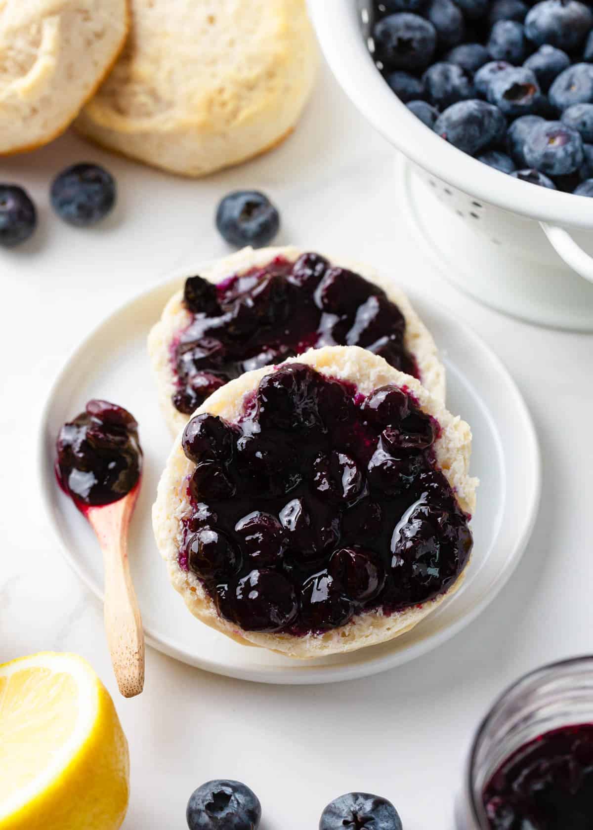 Blueberry jam spread on a biscuit split in half on a plate.