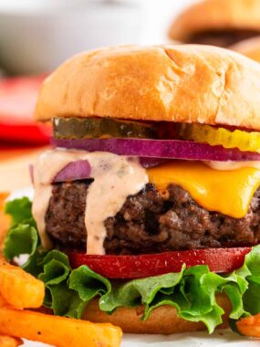 Juicy grilled cheeseburger stacked with lettuce, tomato, red onion, and pickles on a toasted brioche bun.