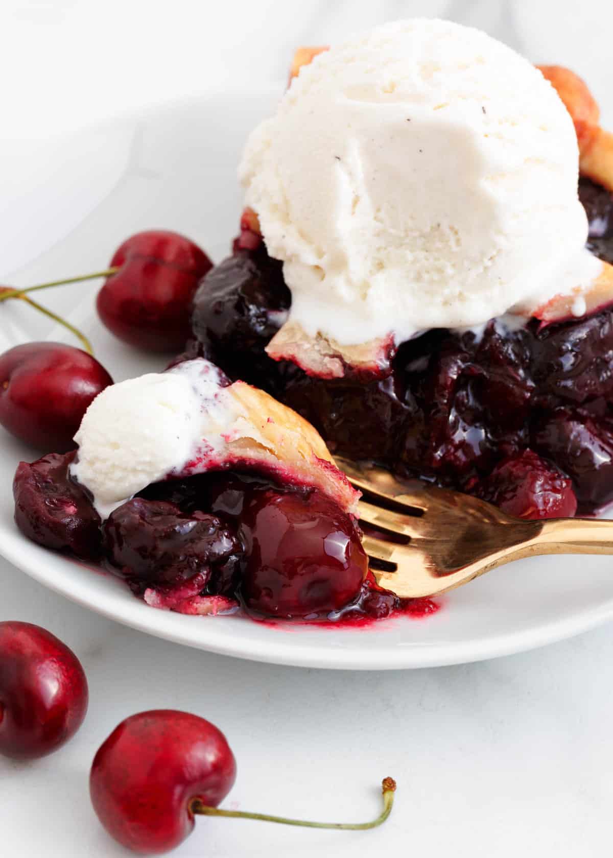 Cherry pie filling on a white plate with ice cream. 