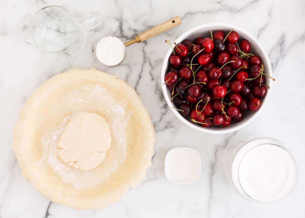 Cherry pie ingredients on a marble counter.