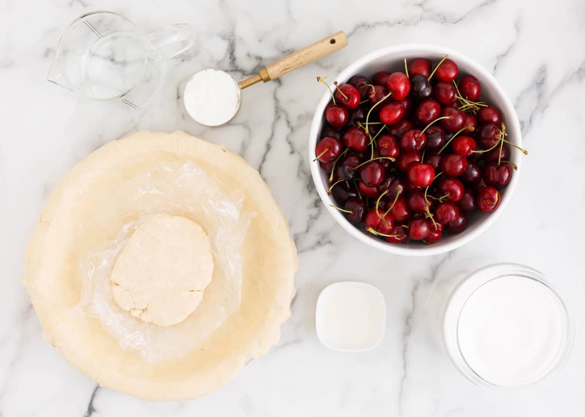 Cherries, sugar, cornstarch, water and pie crust on the counter.