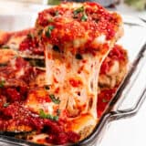 Pulling eggplant parmesan out of baking dish.