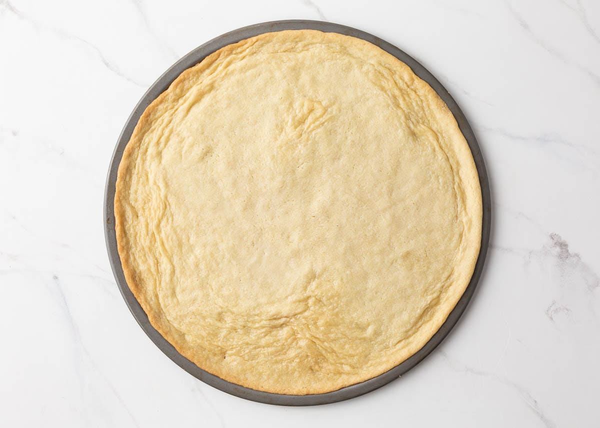 Baked sugar cookie dough on a pizza pan.