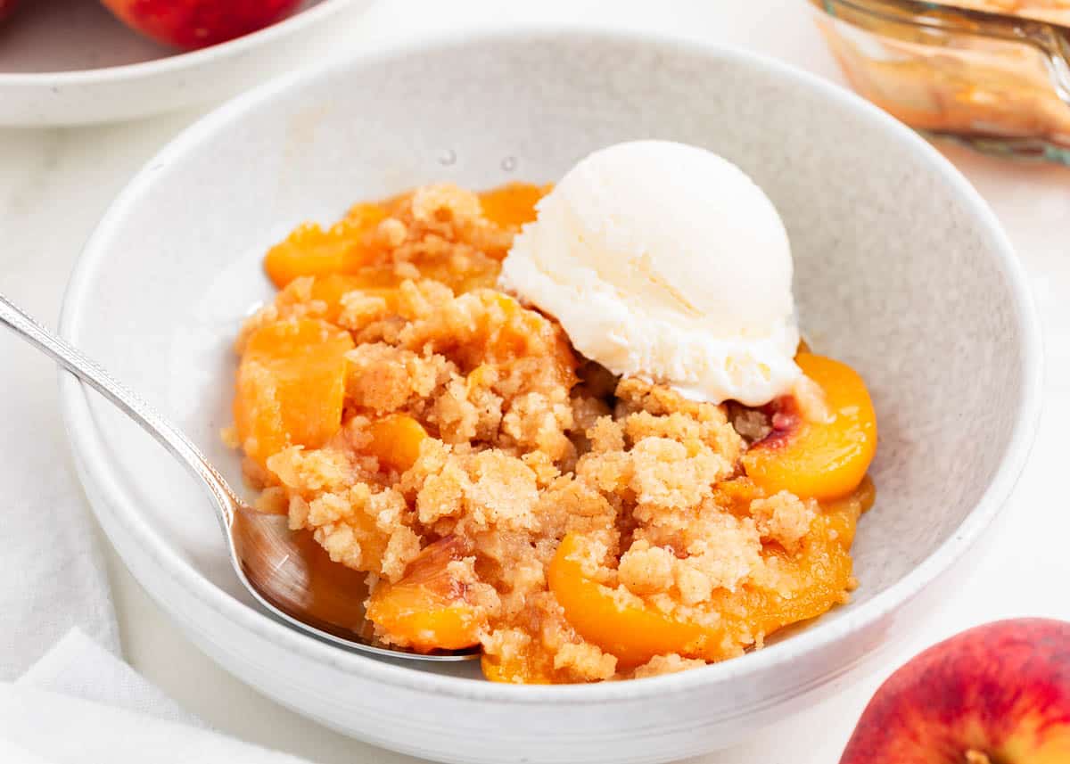 Peach cobbler and ice cream in a bowl.